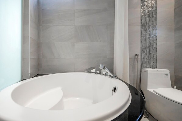 A modern bathroom with a large oval sink, a toilet, and a shower area.