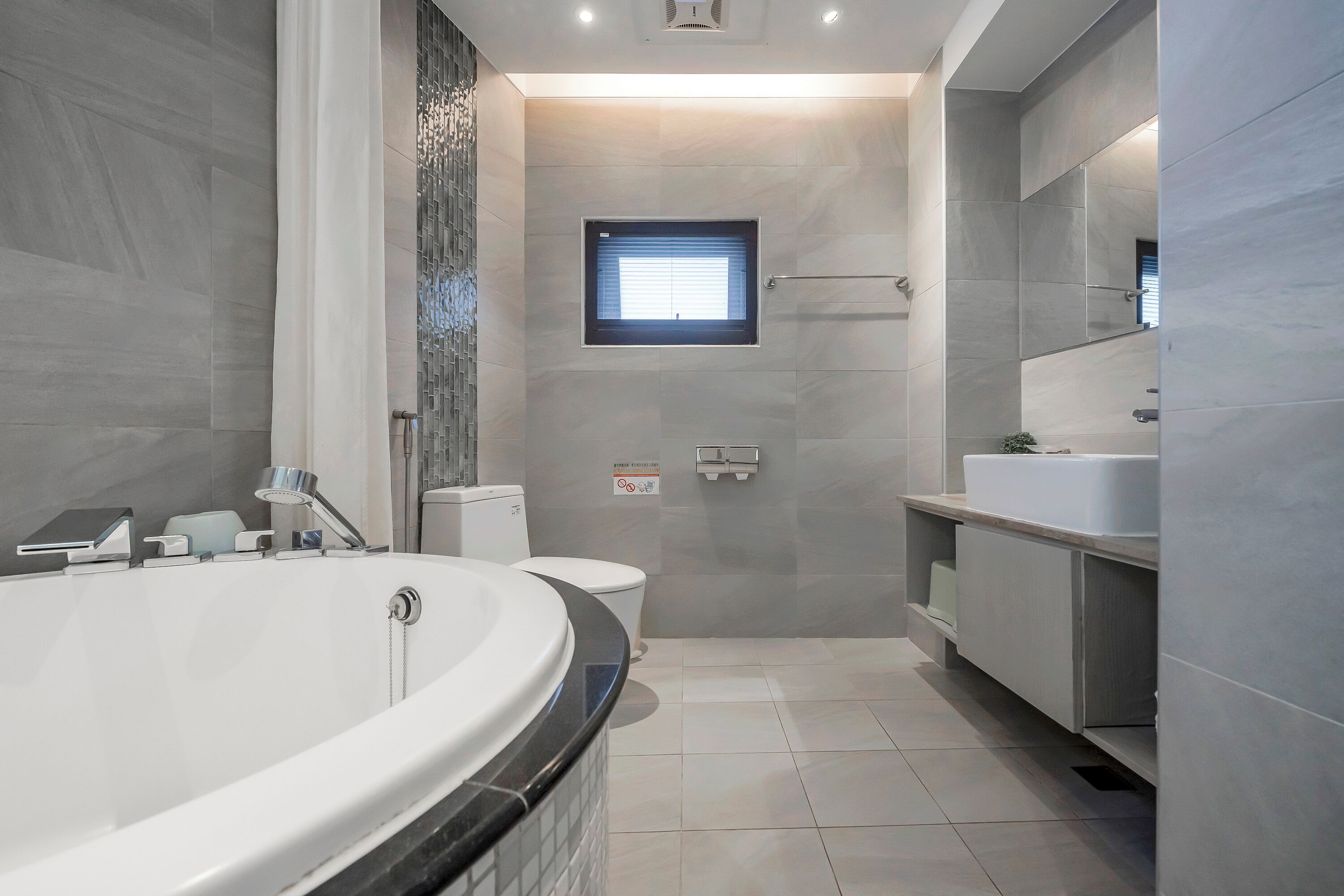 Een moderne badkamer met een vrijstaand bad, toilet en wastafel.