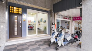 L'ingresso di un edificio con una porta scura, una porta in vetro e un pavimento piastrellato.
