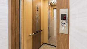 Interno di un ascensore con pareti in legno, un display digitale e una ringhiera.