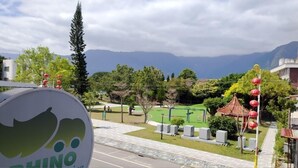 Vista di un parco con un campo da basket, un grande albero e una montagna sullo sfondo.