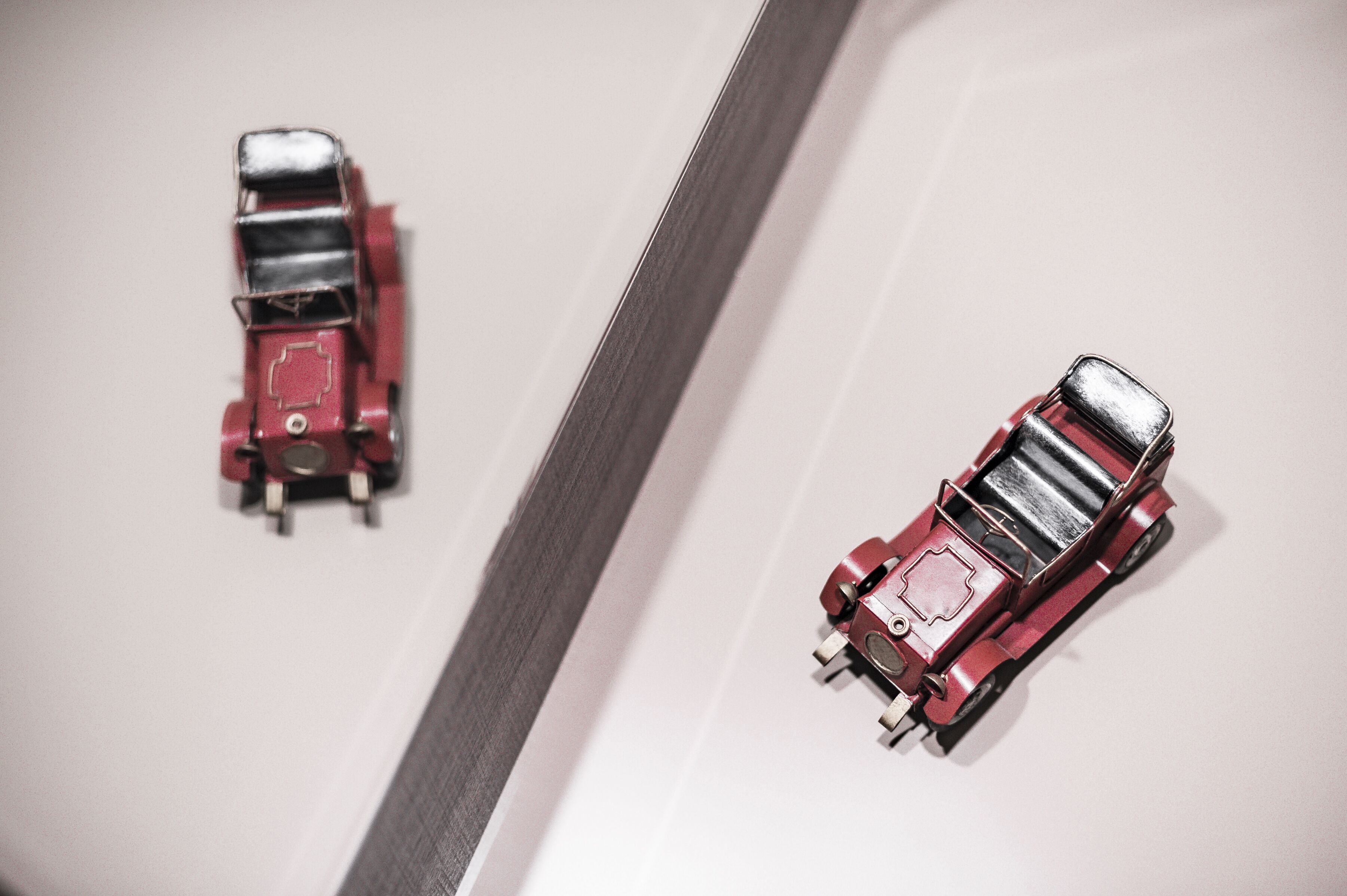 Two red toy cars on a white surface.