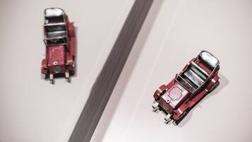 Two red toy cars on a white surface.