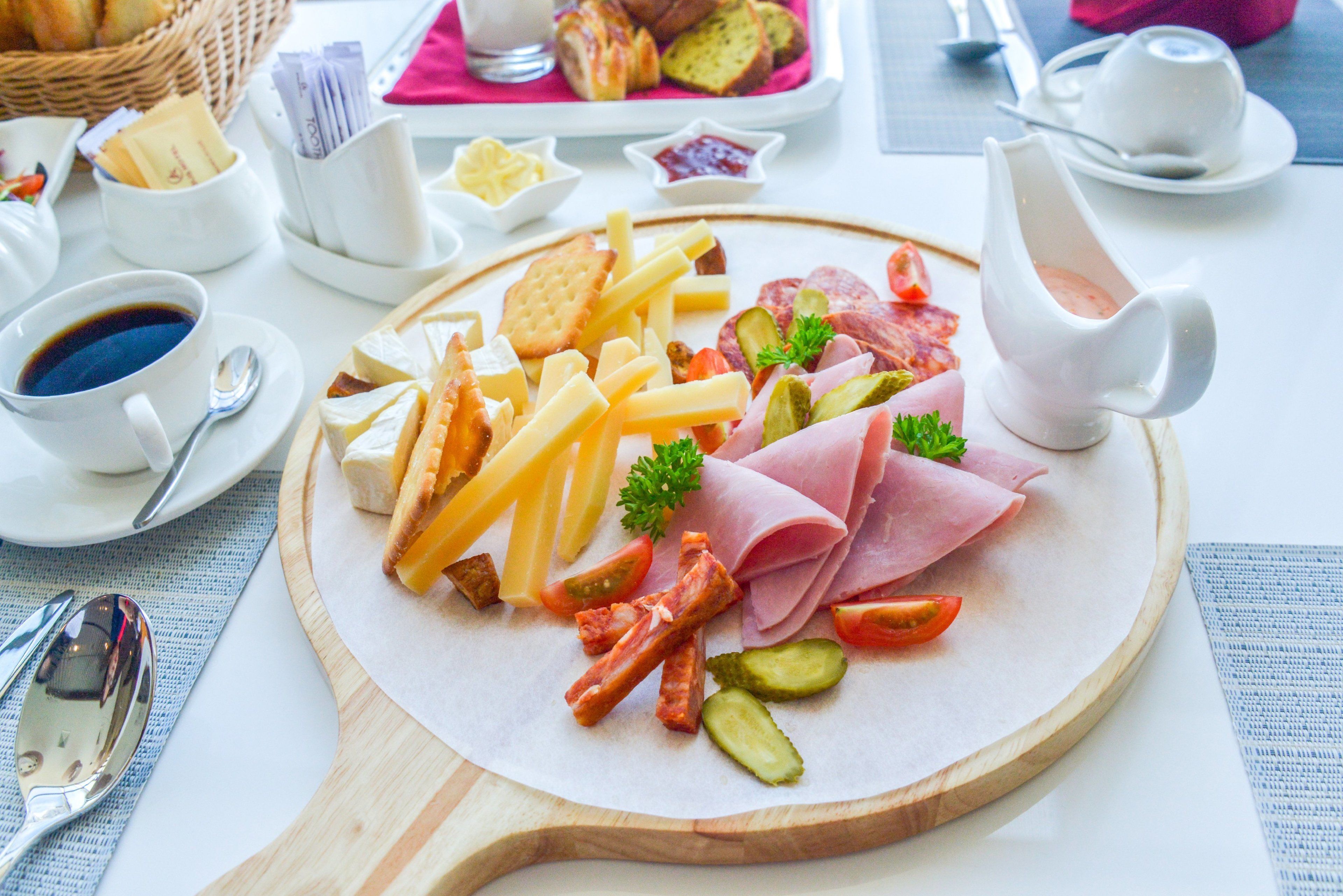 Een charcuteriebord met verschillende vleessoorten, kazen en ingelegde groenten.