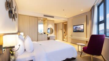 Une chambre d’hôtel avec un grand lit, un bureau, une chaise et un téléviseur.