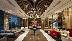 A modern lobby with a central floral arrangement, a chandelier, and a mix of seating areas. - DQua Hotel (Nha Trang)