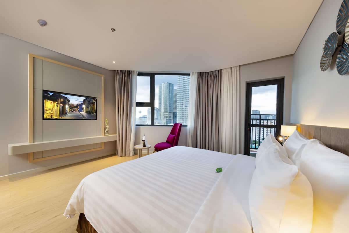 A hotel room with a large bed, a television mounted on the wall, a window with curtains, and a city view.