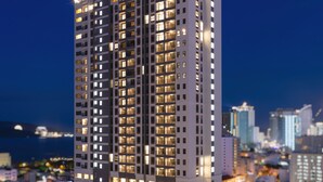 A high-rise building with multiple floors, large windows, and a well-lit facade. - DQua Hotel (Nha Trang)