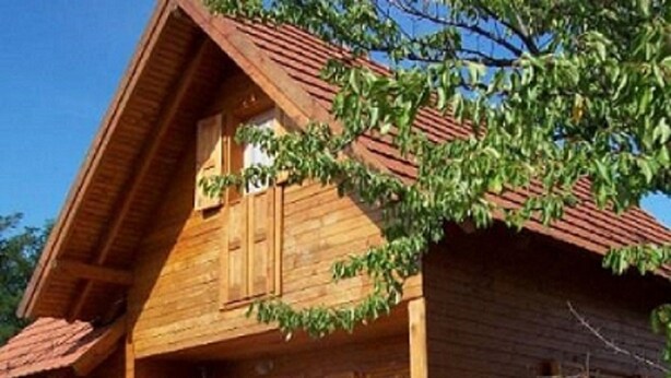 A wooden house with a sloped roof and a large wooden door. - Apartman Daniel (Balatonfokajár)