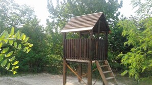 A wooden playhouse with a sloped roof and a ladder. - Apartman Daniel (Balatonfokajár)