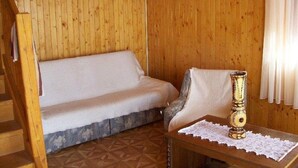 A wooden room with a sofa, a chair, a table with a vase, and a staircase. - Apartman Daniel (Balatonfokajár)