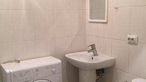 A small, clean bathroom with a washing machine, sink, and toilet. - Moisha Apartment Kotlyarskaya 8-14 (Lviv)