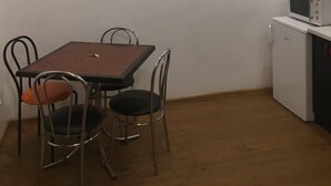 A small dining area with a table and four chairs, a microwave on a small cabinet, and a ceiling with recessed lighting. - Moisha Apartment Kotlyarskaya 8-14 (Lviv)