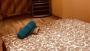 A room with a patterned bedspread, a rolled towel, a television on a stand, and two wall-mounted lamps. - Moisha Apartment Kotlyarskaya 10-8 (Lviv)