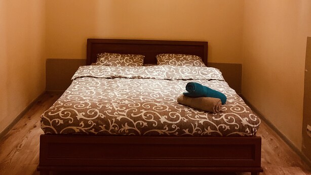 A bedroom with a wooden bed, patterned bedding, and two wall-mounted lamps. - Moisha Apartment Kotlyarskaya 10-8 (Lviv)