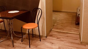A dining area with a table and chairs, a wooden floor, and a curtain in the background. - Moisha Apartment Kotlyarskaya 10-8 (Lviv)