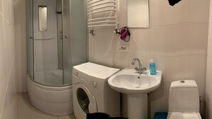 A compact bathroom with a glass-enclosed shower, a washing machine, a sink, and a toilet. - Moisha Apartment Kotlyarskaya 10-8 (Lviv)