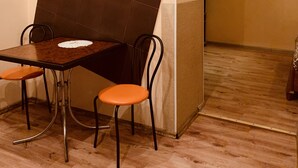 A room with a dining table, two chairs, a small wall-mounted shelf, and a curtain on the wall. - Moisha Apartment Kotlyarskaya 10-8 (Lviv)