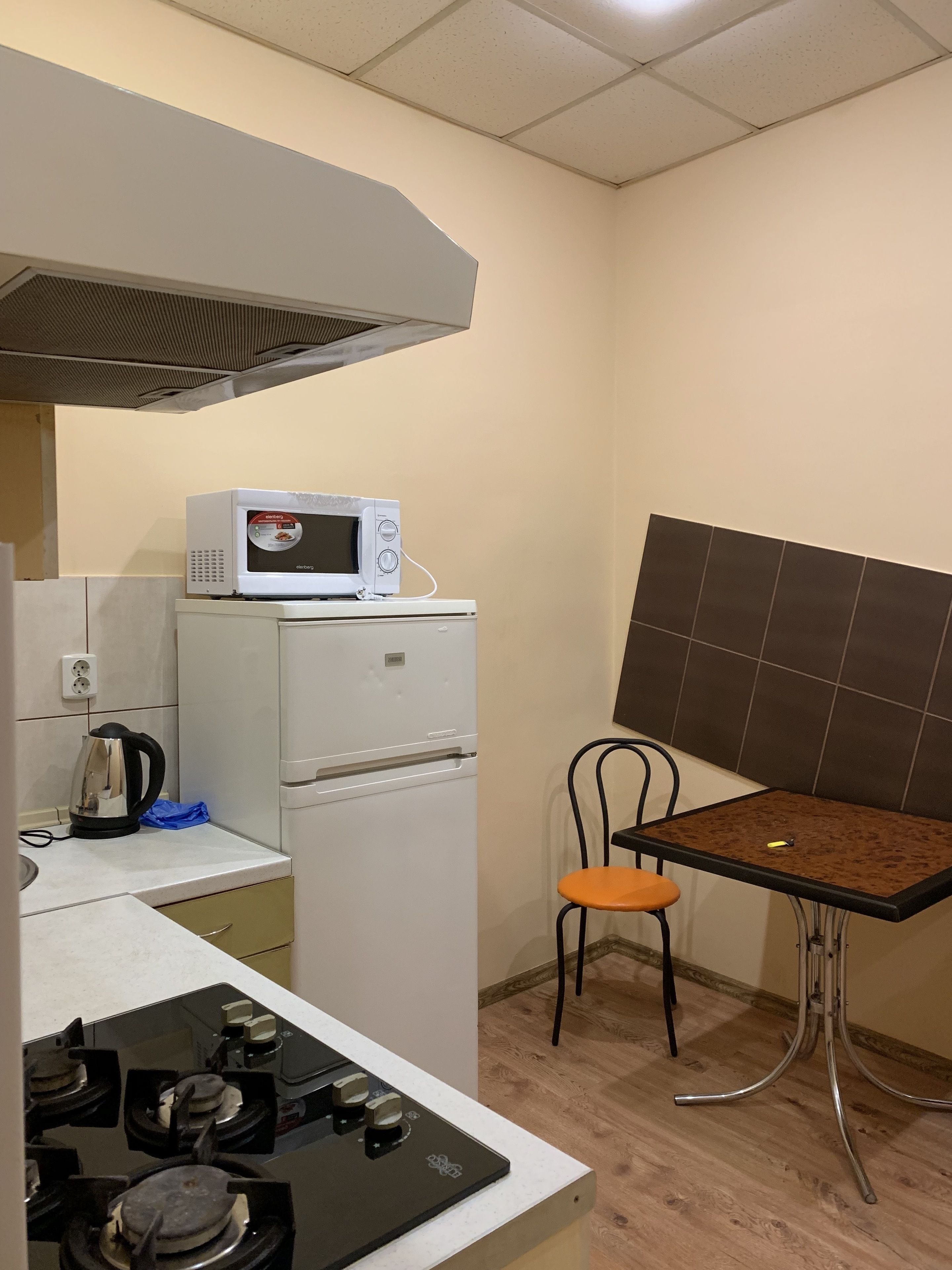 A compact kitchen with a microwave, kettle, and gas stove.