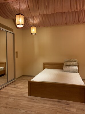 A bedroom with a wooden bed, a large mirror, and two hanging lights. - Moisha Apartment Kotlyarskaya 10-9 (Lviv)