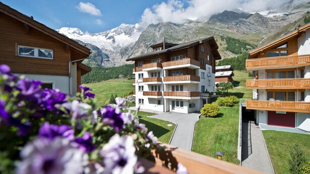 A multi-story hotel with balconies, set against a mountainous backdrop. - Apartment Azurit by Interhome (Saas-Fee)