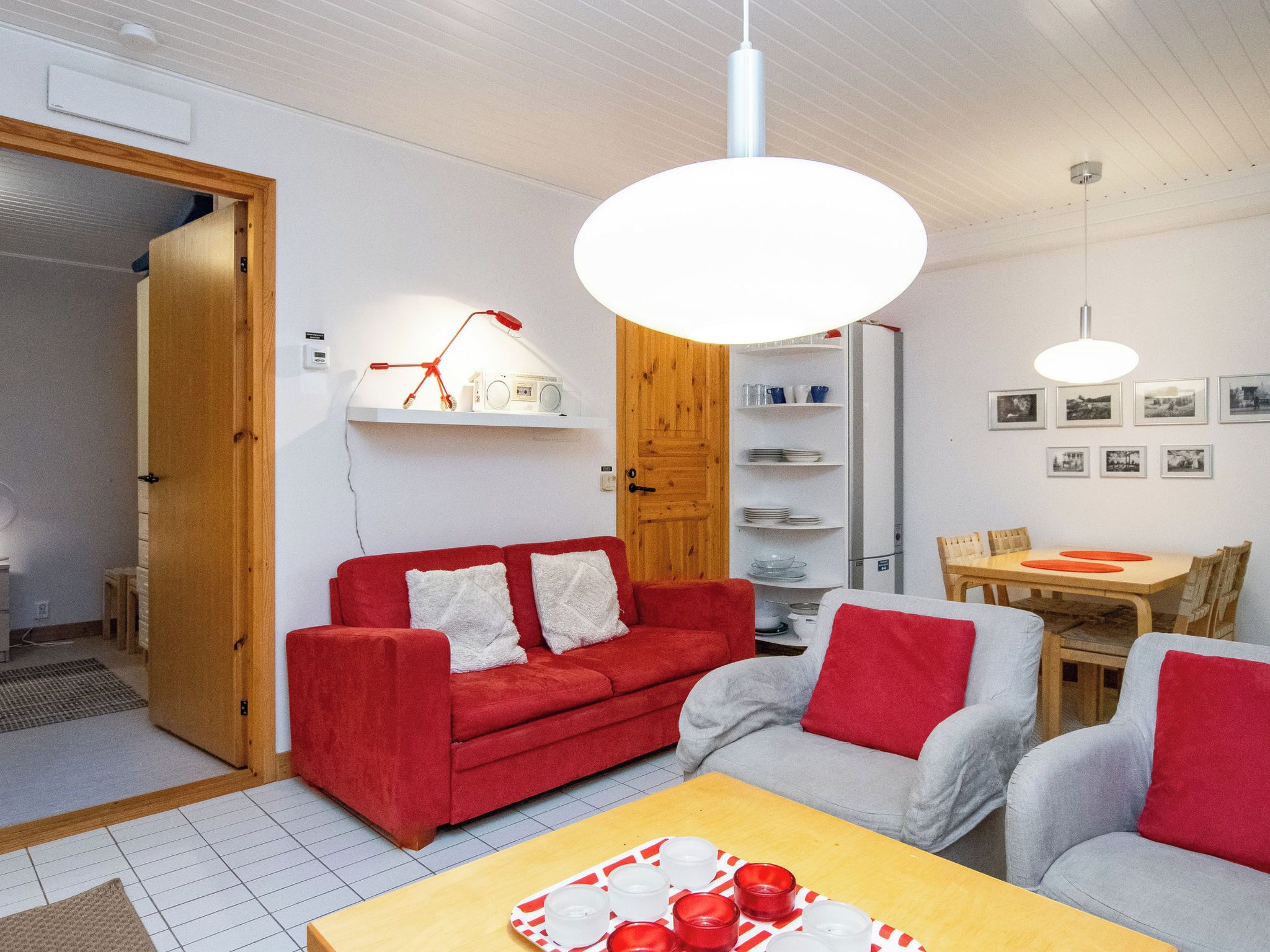 A modern living room with a red sofa, a grey sofa, and a wooden dining table.