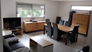 Un espace de vie compact comprenant un téléviseur, des meubles en bois et un coin repas.