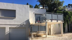 Un bâtiment moderne à deux étages, doté d’un toit plat, d’un espace extérieur couvert et d’un garage.