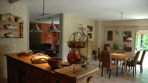 A kitchen with a wooden island, a dining area with chairs, and a view of the outdoors. - Au Picatal (Meyronne)