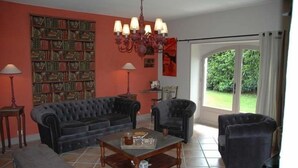 A living room with a dark-colored sofa, a coffee table, and a bookshelf against a red wall. - Au Picatal (Meyronne)