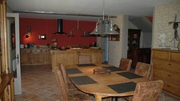 Ein Essbereich mit Holztisch und -stühlen, im Hintergrund eine Küche und eine rote Wand.