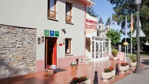 A hotel with a stone facade, a red entrance, and a bell tower. - Hotel Alvaro (Cudillero)