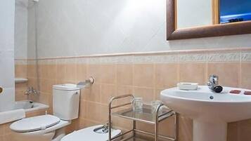 A bathroom with a sink, two toilets, a shower, and a mirror.