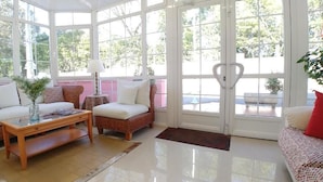 A sunlit room with wicker furniture, a glass coffee table, and a view through large windows. - Hotel Alvaro (Cudillero)