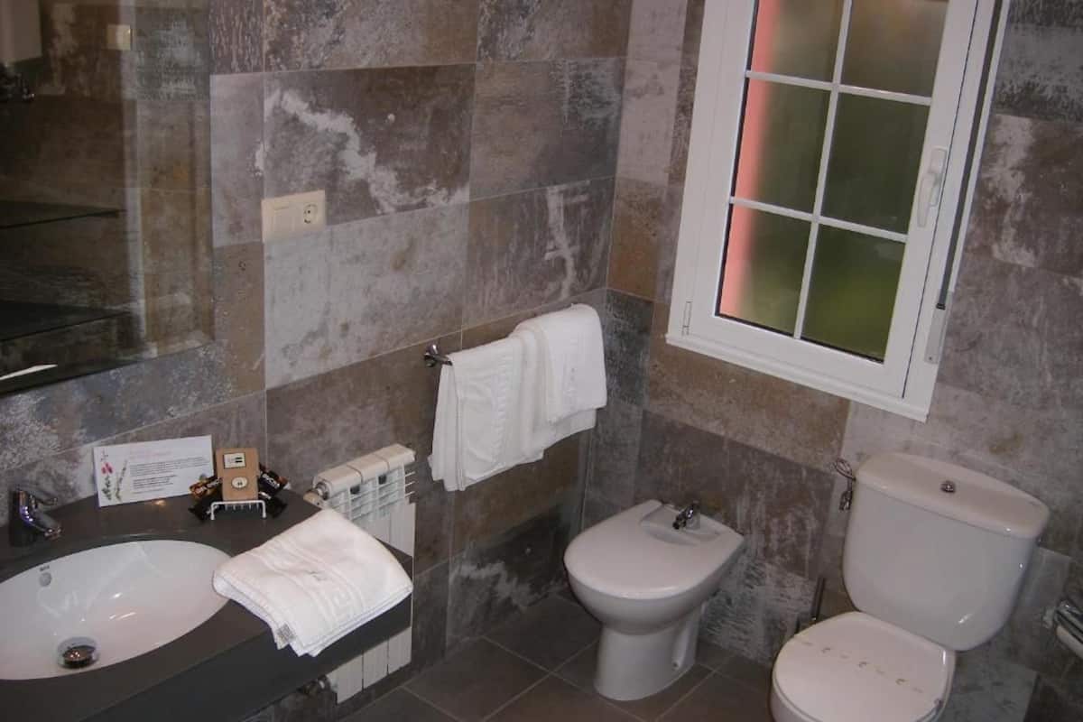 A bathroom with a large sink, two toilets, and a bidet.