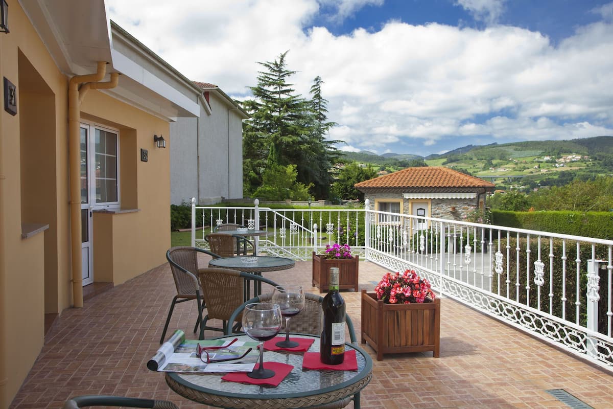A terrace with outdoor seating, a table with wine glasses and a bottle, and a view of the countryside.