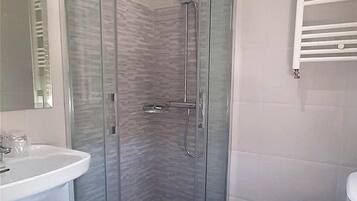 A modern bathroom with a glass-enclosed shower, a white sink, and a toilet.