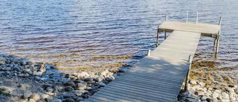 Un muelle de madera se adentra en aguas tranquilas, rodeado de rocas.