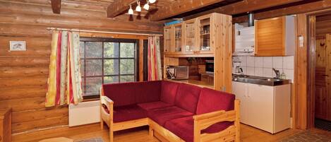 Ein gemütliches Blockhauss-Interieur mit einer Holz-Couch, einer Küchenzeile und einem Fenster mit Vorhängen.