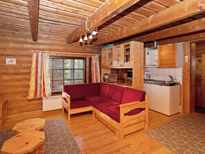 A cozy cabin interior with a wooden sofa, a kitchenette, and a window with curtains. - Metsämaja by Interhome (Kuusamo)