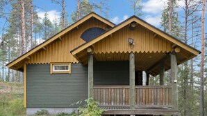 Una baita di legno con veranda, immersa tra gli alberi.