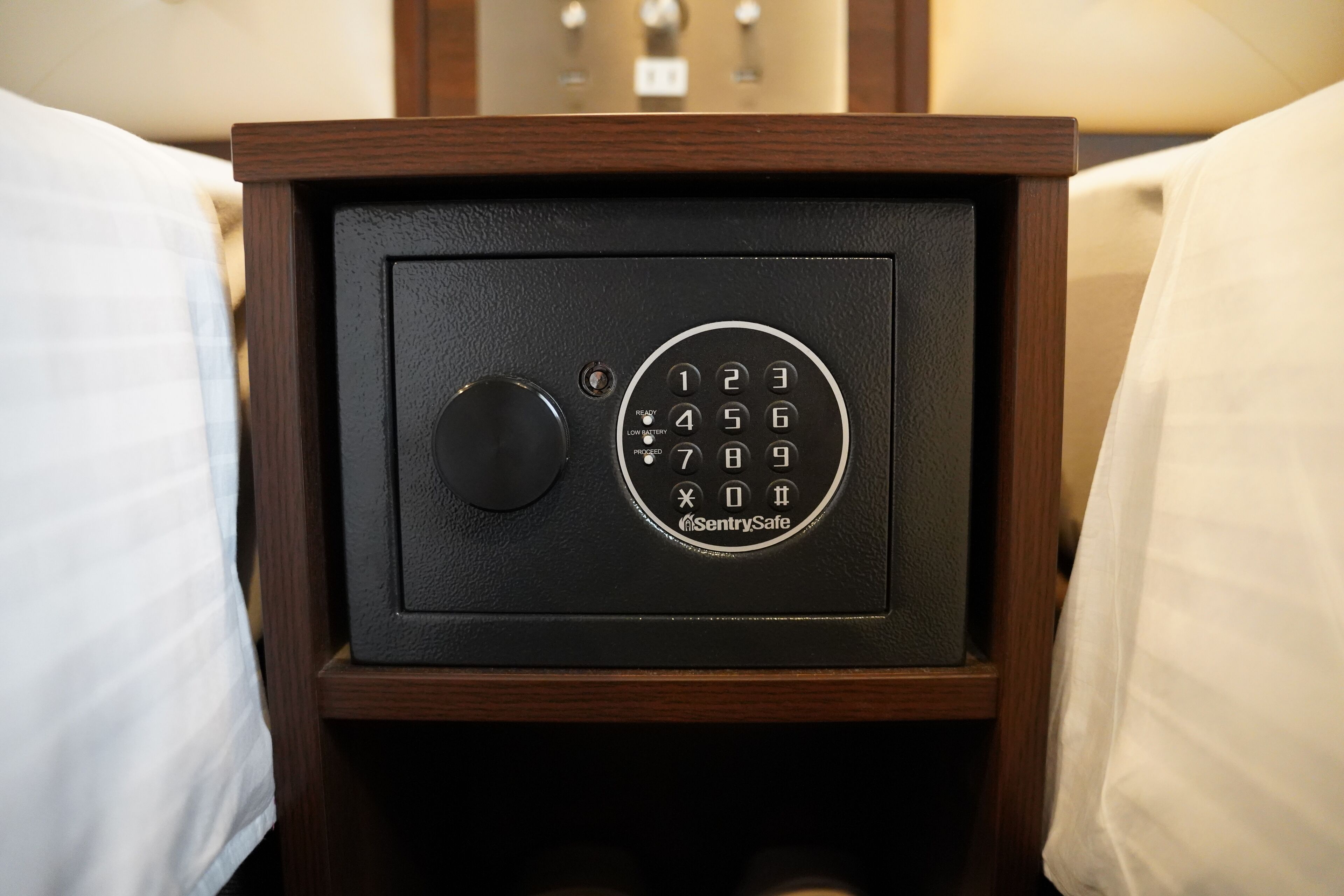 A safe with a keypad and a lock button, placed in a wooden cabinet.