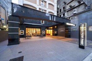 L’extérieur de l’hôtel Welina Premier se distingue par son design moderne, avec une façade en verre, un espace extérieur aménagé et une entrée imposante.