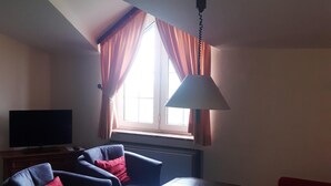 A living room with a television, two sofas, a coffee table, and a window with curtains. - Haus Seeblick (Neuwerk)