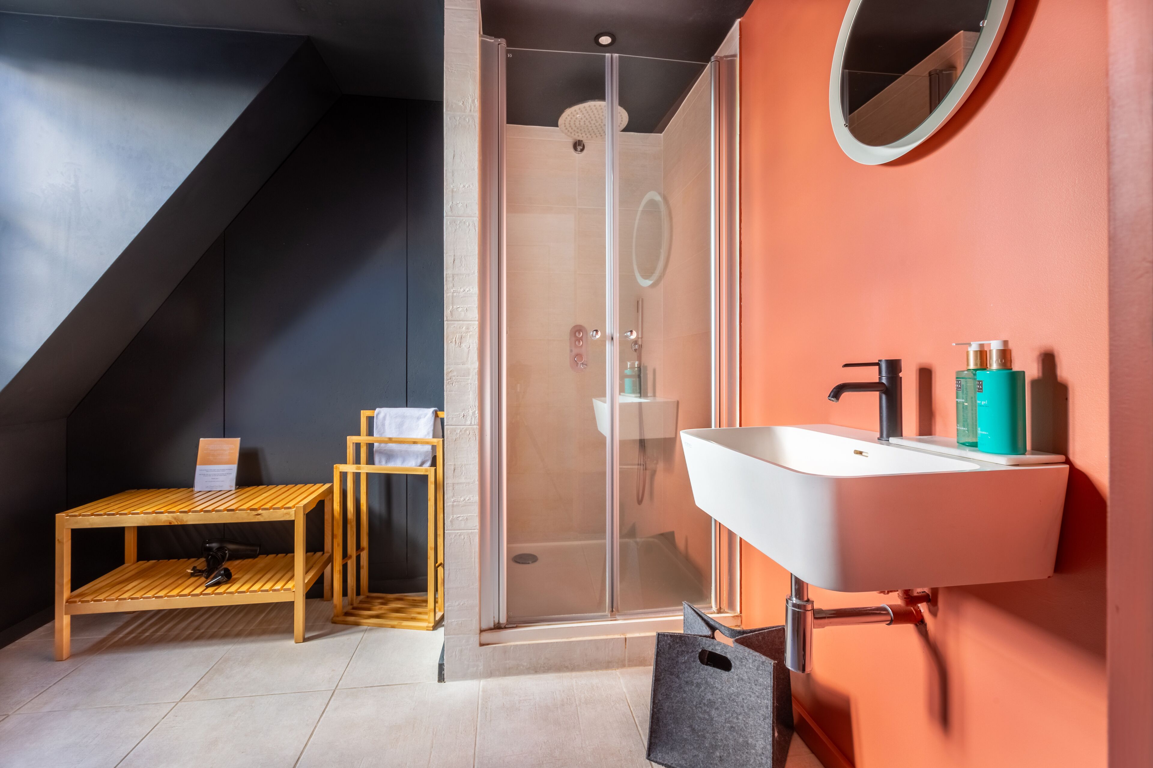 Une salle de bain moderne avec une douche à parois de verre, un lavabo blanc avec un miroir et des meubles en bois.