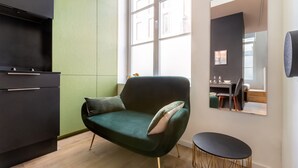 A modern kitchen with a green sofa, a round black table, and a large window. - Au Chat Qui Dort Lille - Magasin  (Lille)