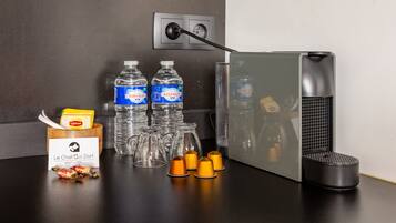 A kitchen counter with a coffee machine, water bottles, a coffee cup, and a box of Lipton tea.
