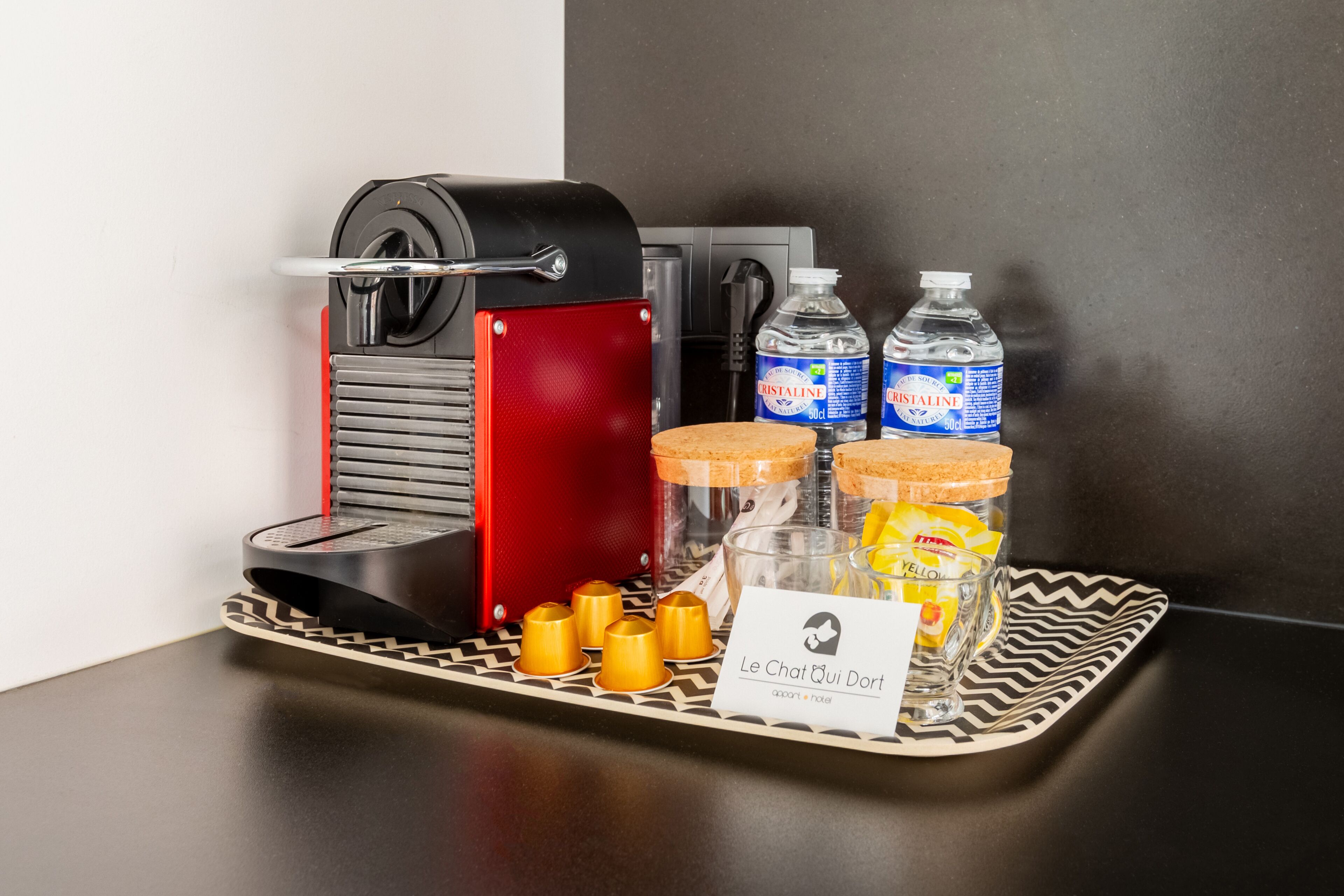 A coffee machine, two bottles of water, a tray with a card, and some snacks.