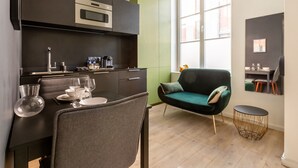 A modern kitchen with a dining area, including a table set for two, a green sofa, and a small side table. - Au Chat Qui Dort Lille - Magasin  (Lille)