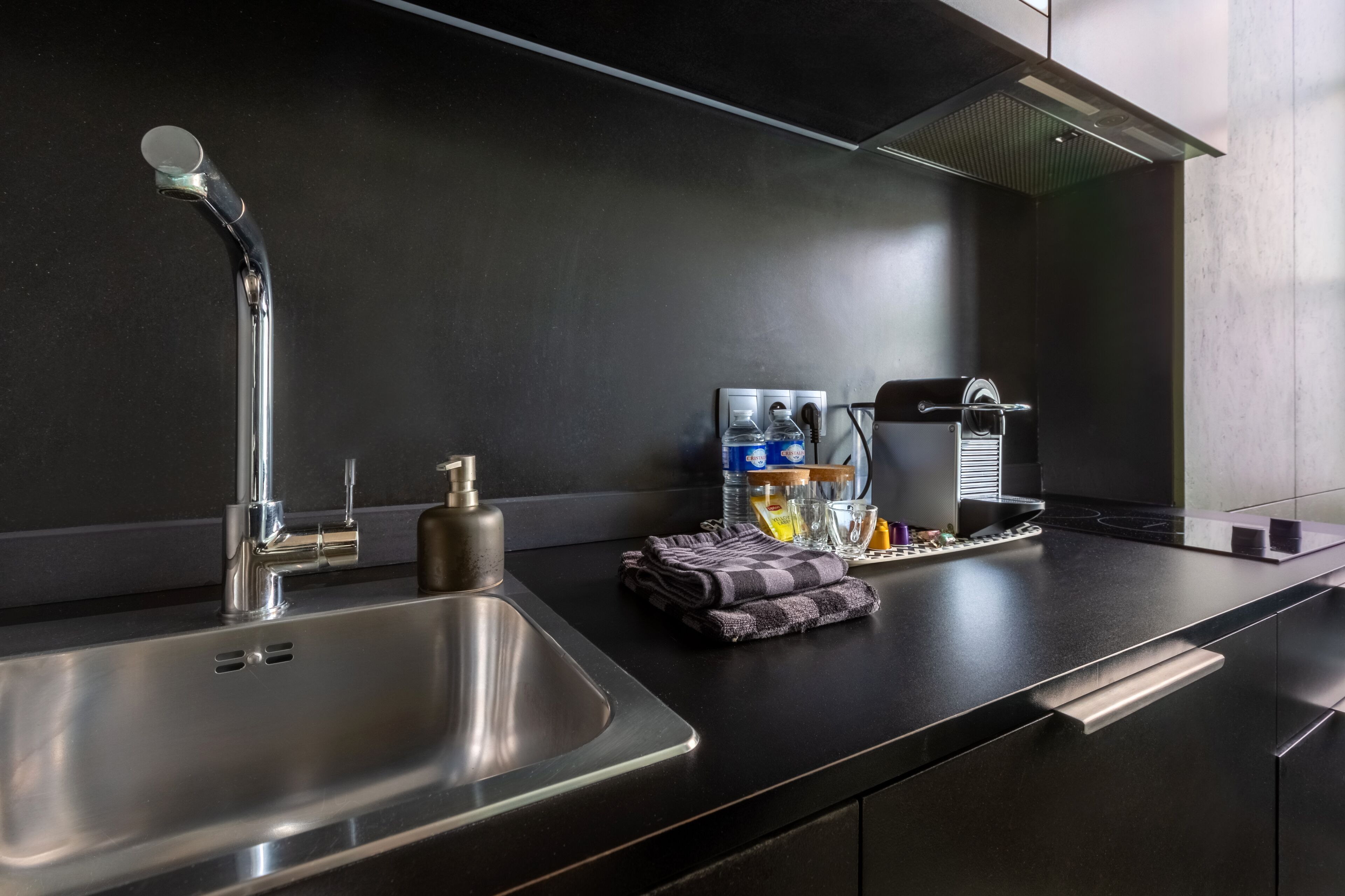 Una cocina moderna con un lavamanos de acero inoxidable, una cafetera y un dispensador de agua.